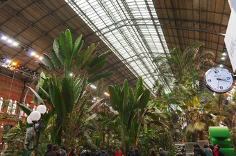 马德里西班牙2月视图的植物花园内部的阿托查火车站与游客和模拟时钟的前景照片采取2月马德里西班牙