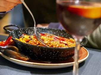 吃valencian西班牙海鲜饭黑色的锅使用叉典型的西班牙语厨房海鲜和旅游