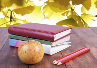 堆栈书铅笔和黄色的苹果系列回来学校堆栈书铅笔和黄色的苹果对的背景秋天叶子