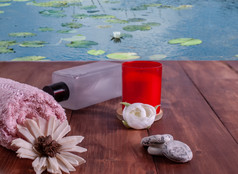 红色的蜡烛与白色花水疗中心石头粉红色的毛巾对的背景池塘与盛开的百合毛巾石头石油和红色的蜡烛