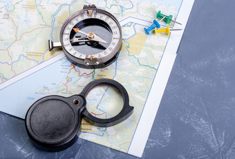 老指南针旅游地图图钉和黑色的折叠放大镜背景为旅行指南针地图放大镜和图钉
