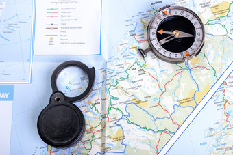 老指南针<strong>旅游地</strong>图图钉和黑色的折叠放大镜背景为旅行指南针地图放大镜和图钉