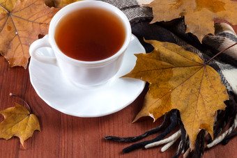 白色杯与茶和围巾木背景与秋天叶子杯与茶的表格与秋天叶子
