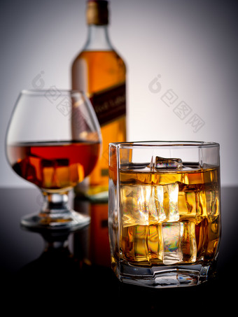 玻璃威士忌与冰黑暗背景的背景玻璃与威士忌和瓶威士忌特写镜头威士忌煮与冰背景完整的瓶威士忌和填满玻璃