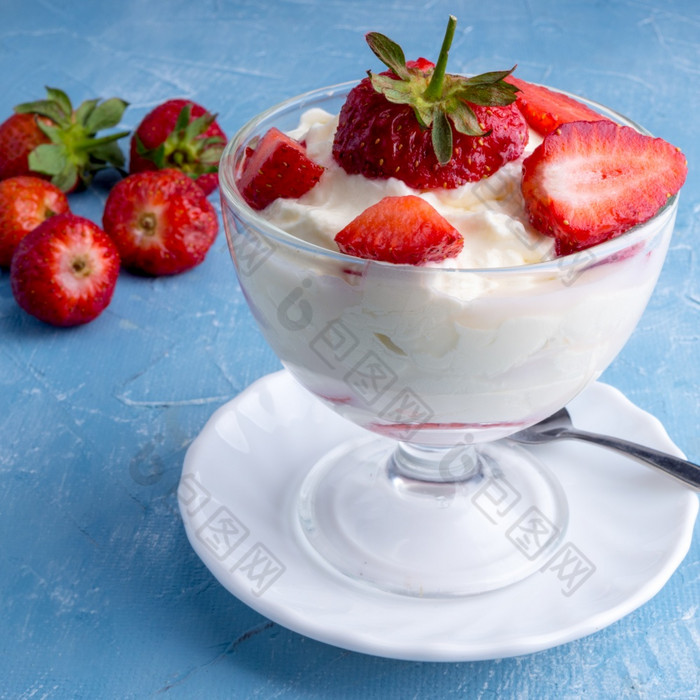 冰奶油碗与草莓蓝色的背景草莓与生奶油玻璃碗