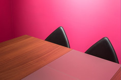 明亮的粉红色的办公室空间与大木桌子上而且艺术角黑色的皮革椅子