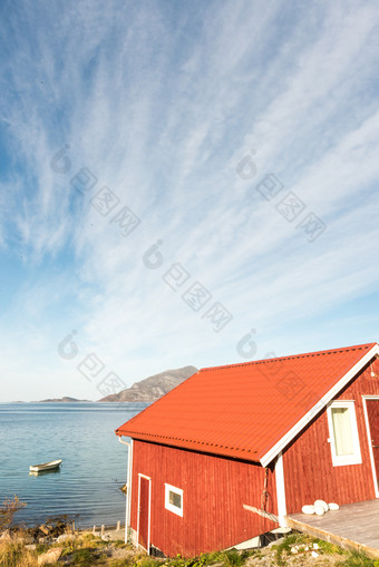 视图木<strong>挪</strong>威海滩小屋与石头的海岸线俯瞰的特罗姆瑟峡湾北极圆<strong>挪</strong>威和山峰阳光明媚的蓝色的天空一天