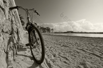 自行车倾斜对石头墙桑迪海滩阳光明媚的一天马略卡岛巴利阿里群岛岛屿西班牙