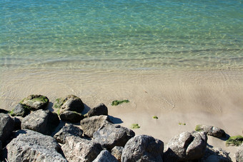 岩石和浅沙子海洋水特写镜头阳光明媚的下午阳光明媚的一天马略卡岛西班牙岩石和浅沙子绿色海洋水