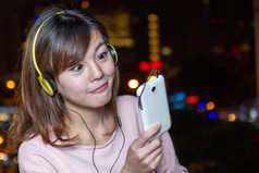 有吸引力的马来西亚女人与黄色的耳机持有手机
