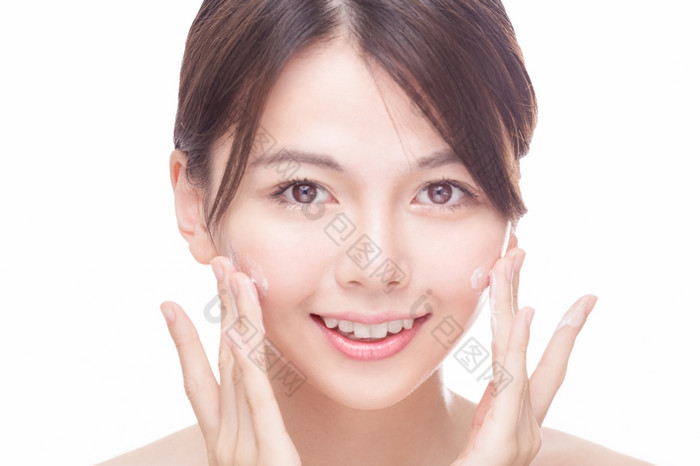 美丽的中国人女人应用奶油脸护肤品概念