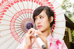 亚洲女人穿和服前面日本房子持有伞