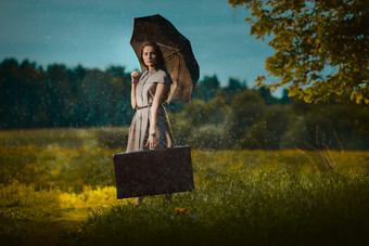 年轻的女人下雨年轻的女人走走了与手提箱下雨