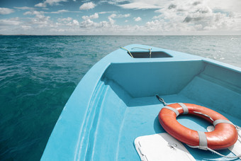 视图的前面蓝色的船与橙色救生圈绿松石水域和遥远的海岸是之前