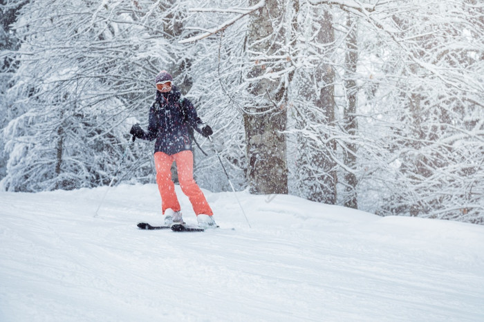 年轻的女滑雪滑动下来的坡下降雪图片