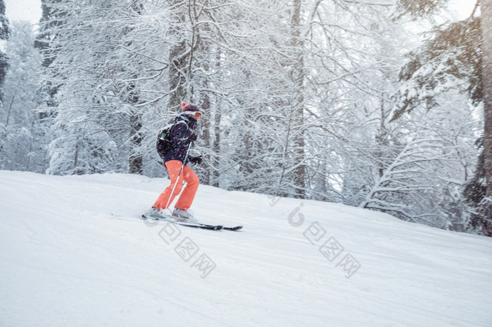 年轻的女滑雪滑动下来的坡下降雪
