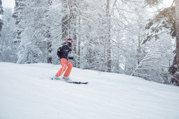 年轻的女滑雪滑动下来的坡下降雪图片