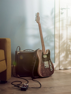 电吉他和放大器站的地板上之间的沙发和通过阳光从的窗口