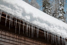 木小屋与雪屋顶和冰柱阳光明媚的冬天一天关闭
