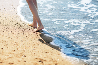 走光着脚沿着的冲浪的沙子海滩
