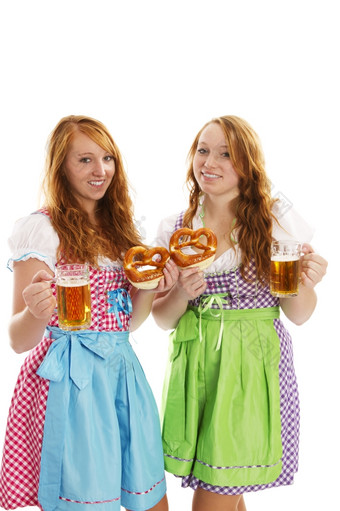 两个巴伐利亚穿着女孩与椒盐卷饼而且啤酒两个巴伐利亚穿着女孩与椒盐卷饼而且啤酒白色背景