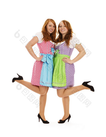 两个巴伐利亚穿着女孩提升他们的脚两个巴伐利亚穿着女孩提升他们的脚白色背景