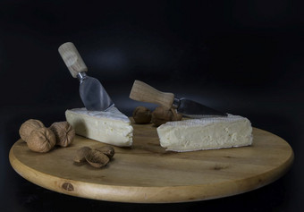 木可旋转的盘与法国奶酪被称为布里干酪与刀和核桃和杏仁法国奶酪与核桃和木盘
