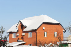 两层楼的红色的砖房子屋顶覆盖与雪阳光明媚的冬天一天俄罗斯