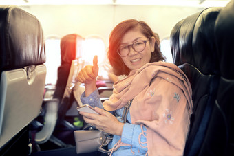 亚洲女人经济类座位国内航空公司飞机标志好感觉手和露出牙齿的微笑脸
