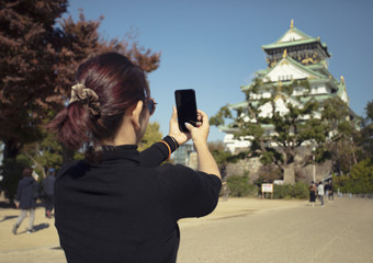女人旅游采取照片<strong>大阪城堡</strong>聪明的电话<strong>大阪城堡</strong>一个大多数受欢迎的旅行目的地日本