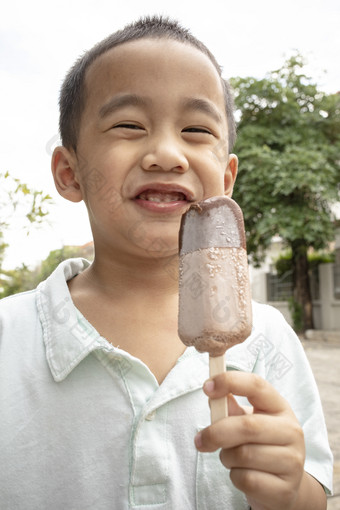 关闭脸亚洲男孩吃巧克力冰淇淋与幸福脸