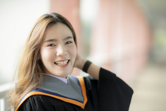 露出牙齿的微笑脸美丽的亚洲年轻的女人穿大学毕业衣服幸福情感