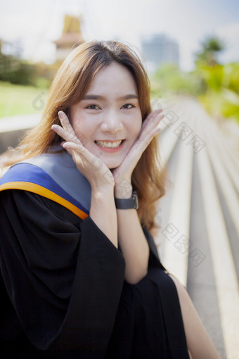 幸福微笑脸亚洲年轻的女人穿大学gruation西装