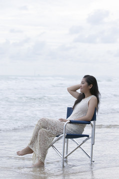 亚洲年轻的女人坐着放松椅子海海滩假期时间