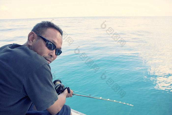男人。和钓鱼杆手与宽蓝色的海场景男人。和钓鱼杆手与宽蓝色的海场景