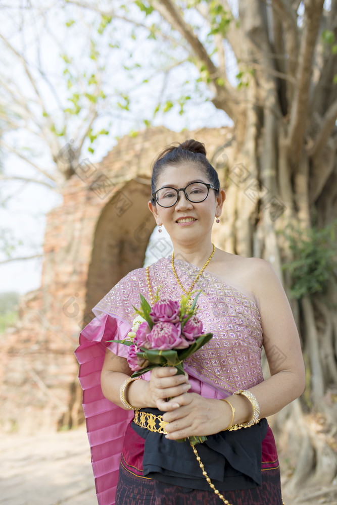 泰国女人露出牙齿的微笑脸站与粉红色的莲花花花束手
