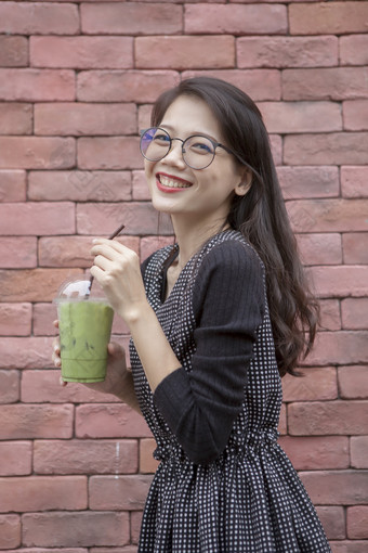 年轻的亚洲女人和眼镜冰绿色茶饮料手