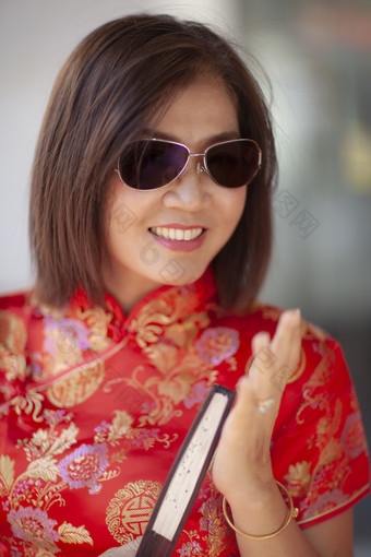 亚洲女人穿中国人传统衣服与中国人竹子风扇露出牙齿的微笑脸耀华力街中国小镇曼谷泰国