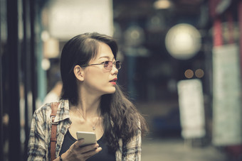 关闭脸亚洲年轻的女人持有聪明的电话手走购物区域