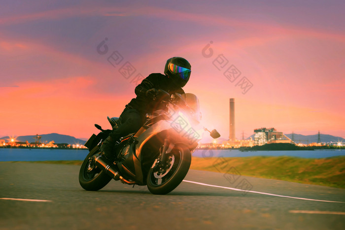 年轻的男人。骑体育运动巡回演出摩托车沥青高速公路对美丽的照明城市行业场景使用现代人生活方式和假期活动