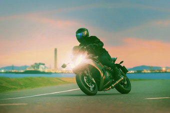 年轻的男人。骑体育运动巡回演出摩托车沥青高速公路对美丽的照明城市行业场景使用现代人生活方式和假期活动