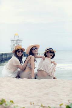 三个美丽的亚洲年轻的女人笑与放松情感假期海一边
