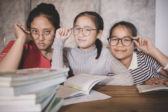快乐的亚洲少年穿眼睛眼镜与学校书首页生活房间