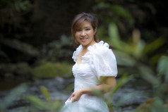美丽的亚洲年轻的女人穿白色衣服站绿色自然背景