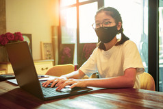 亚洲少年穿保护面具打字电脑移动PC工作从首页