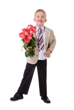 可爱的笑小穿着考究的男孩站与大花束红色的玫瑰