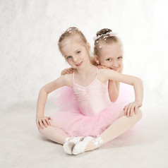 两个小女孩芭蕾舞 演员坐着的图图的地板上