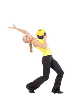 健身与医学球美丽的优雅的年轻的女人做练习与球黄色的而且黑色的颜色