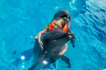 <strong>小微</strong>笑女孩游泳与的海豚的游泳池的明亮的阳光明媚的一天