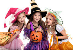 三个美丽的微笑小女孩与长头发的色彩斑斓的女巫服装看相机与技巧治疗袋而且杰克rsquo灯笼